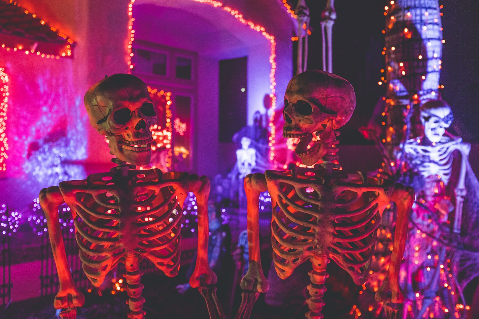 two skeleton near white concrete building with string lights
