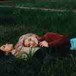 two women lying on green grass