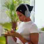 woman in white crew neck t-shirt holding smartphone listening to podcasts