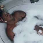 woman in white bathtub with water - self care mental health tips