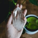 a person holding a piece of crystal next to a potted plant