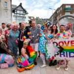 Image of Dover Pride March 2022 in Market Square with the team. Holding Dover Pride flag.