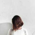 woman in white shirt leaning on wall during daytime