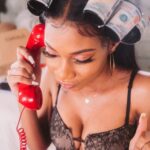 woman in black and white floral brassiere holding red plastic bottle