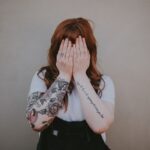 woman covering her face in front of wall