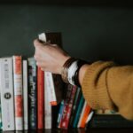 self help books -person picking white and red book on bookshelf