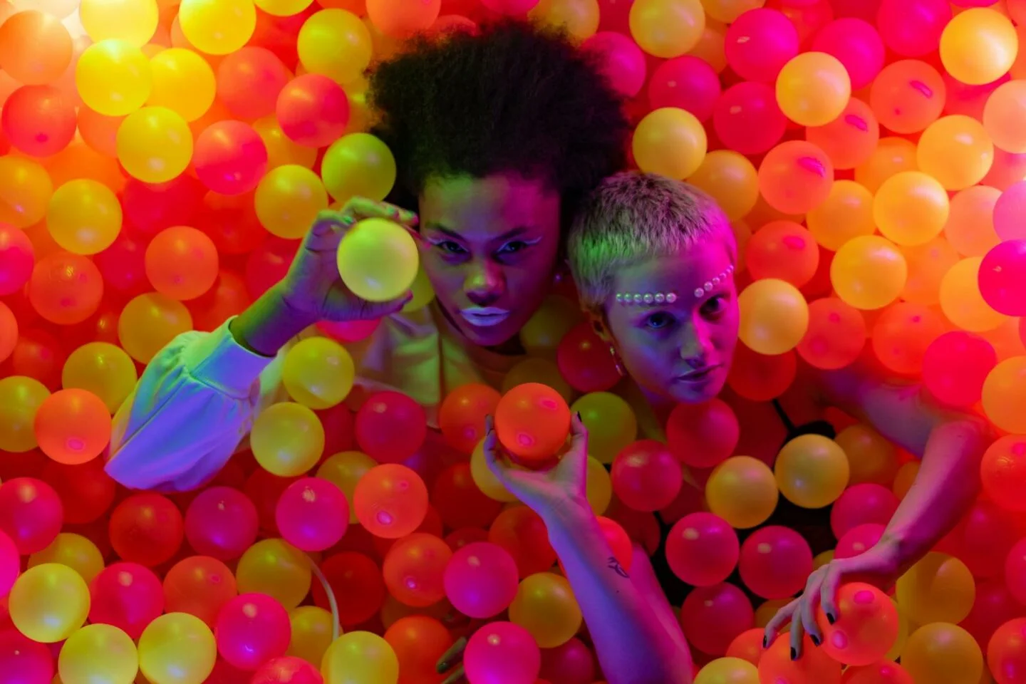 Women Holding Colorful Balls while Seriously Looking at the Camera
