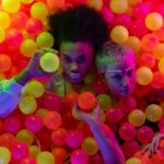 Women Holding Colorful Balls while Seriously Looking at the Camera