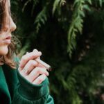 a woman in a green jacket holding a cigarette