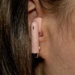 A close up of a woman's ear with a pink device attached to it