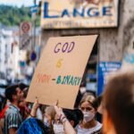 woman in holding a banner that says god is non-binary