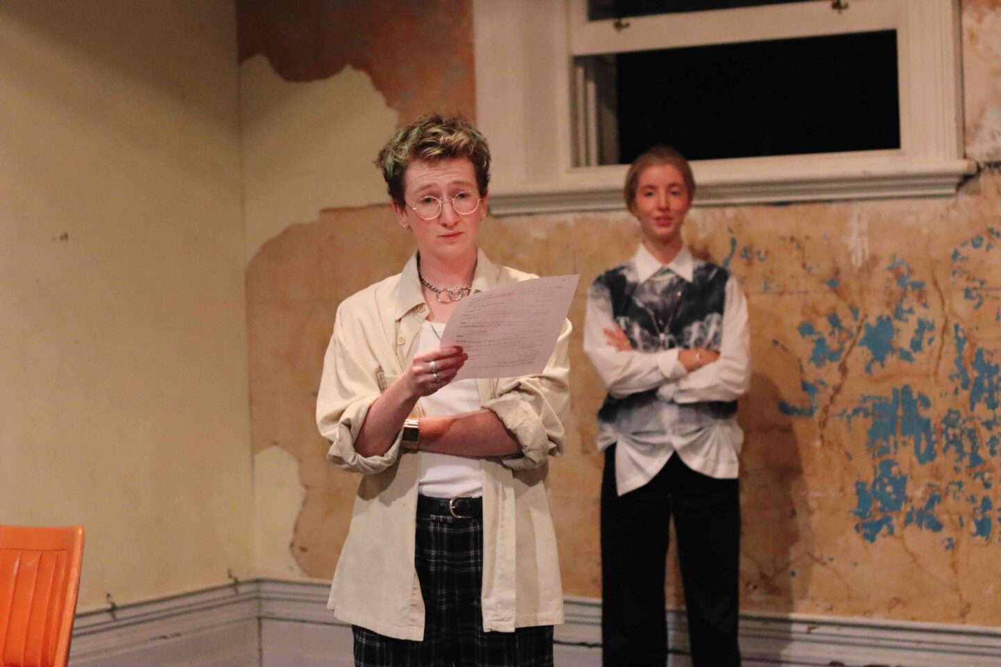 two women in shirts, one is holding a piece of paper