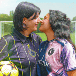 two women about to kiss wearing football shirts