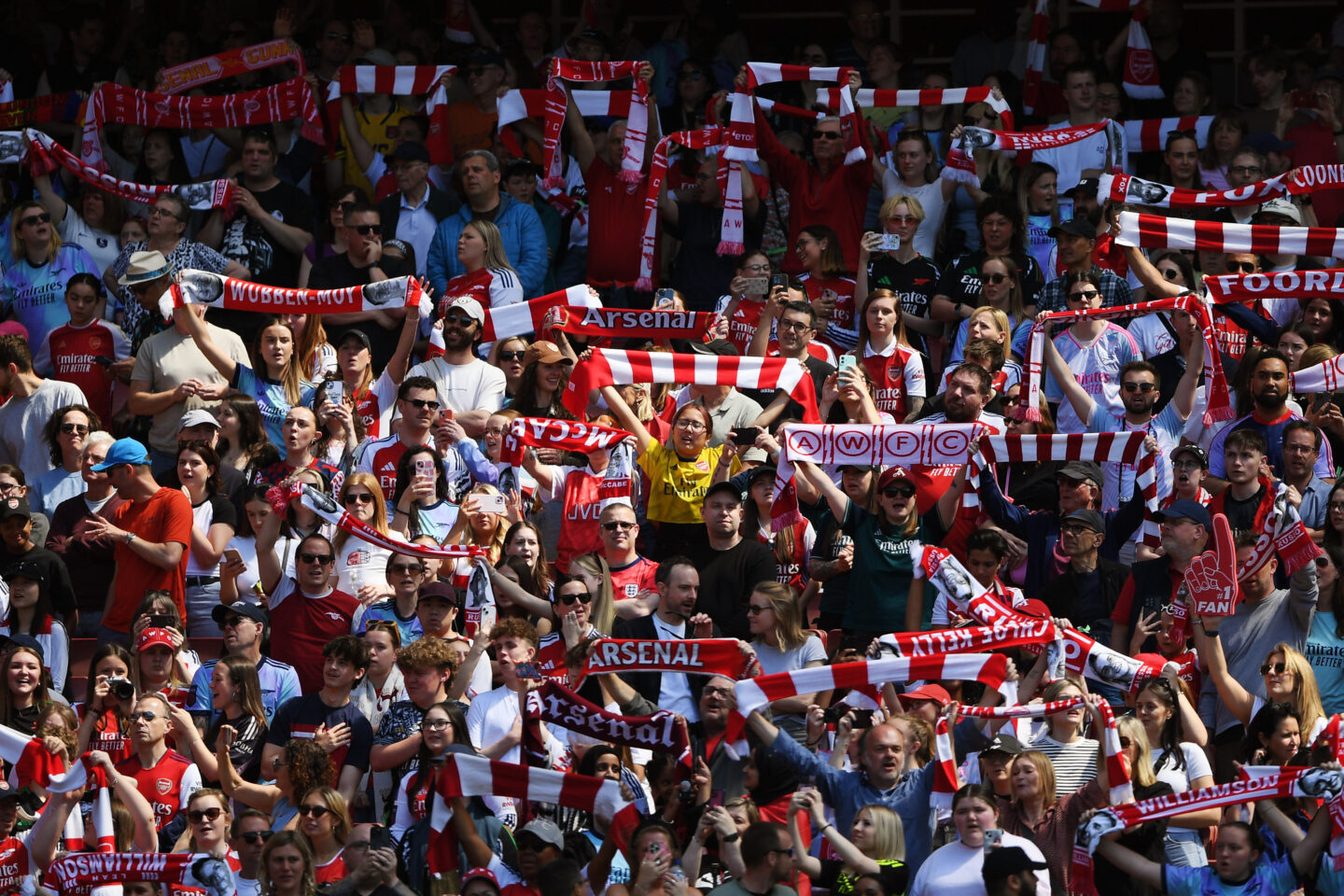 Arsenal fans holding scarfs in the crowd