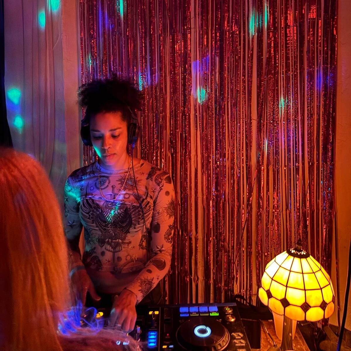 a DJ at decks and a lamp