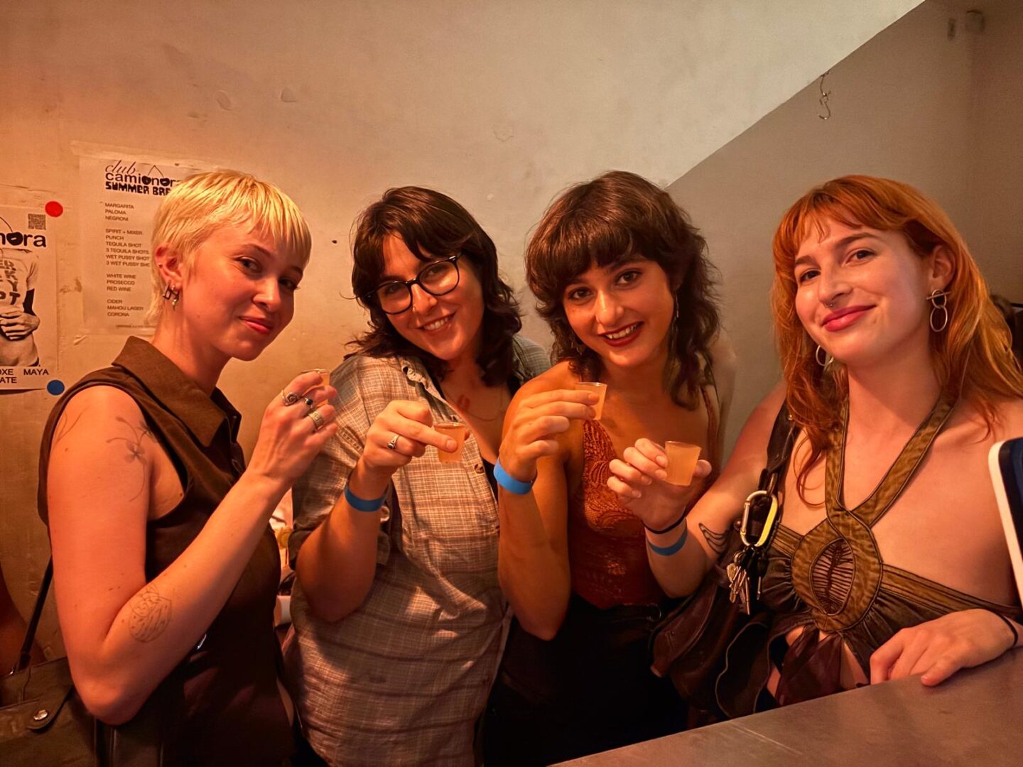 people holding shots in their hands in a bar