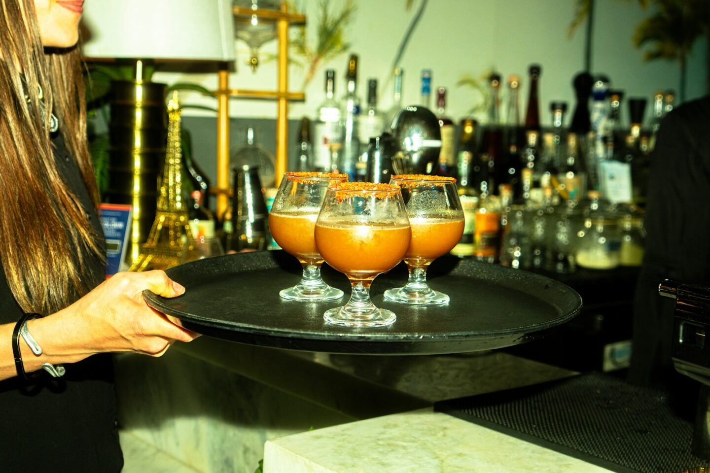 A waitress carries cocktails on a tray.