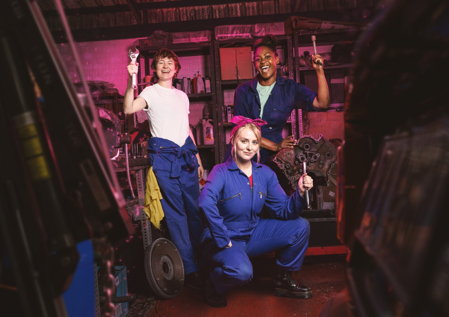 Gwenda’s Garage. Women standing holding tolls in a car garage.