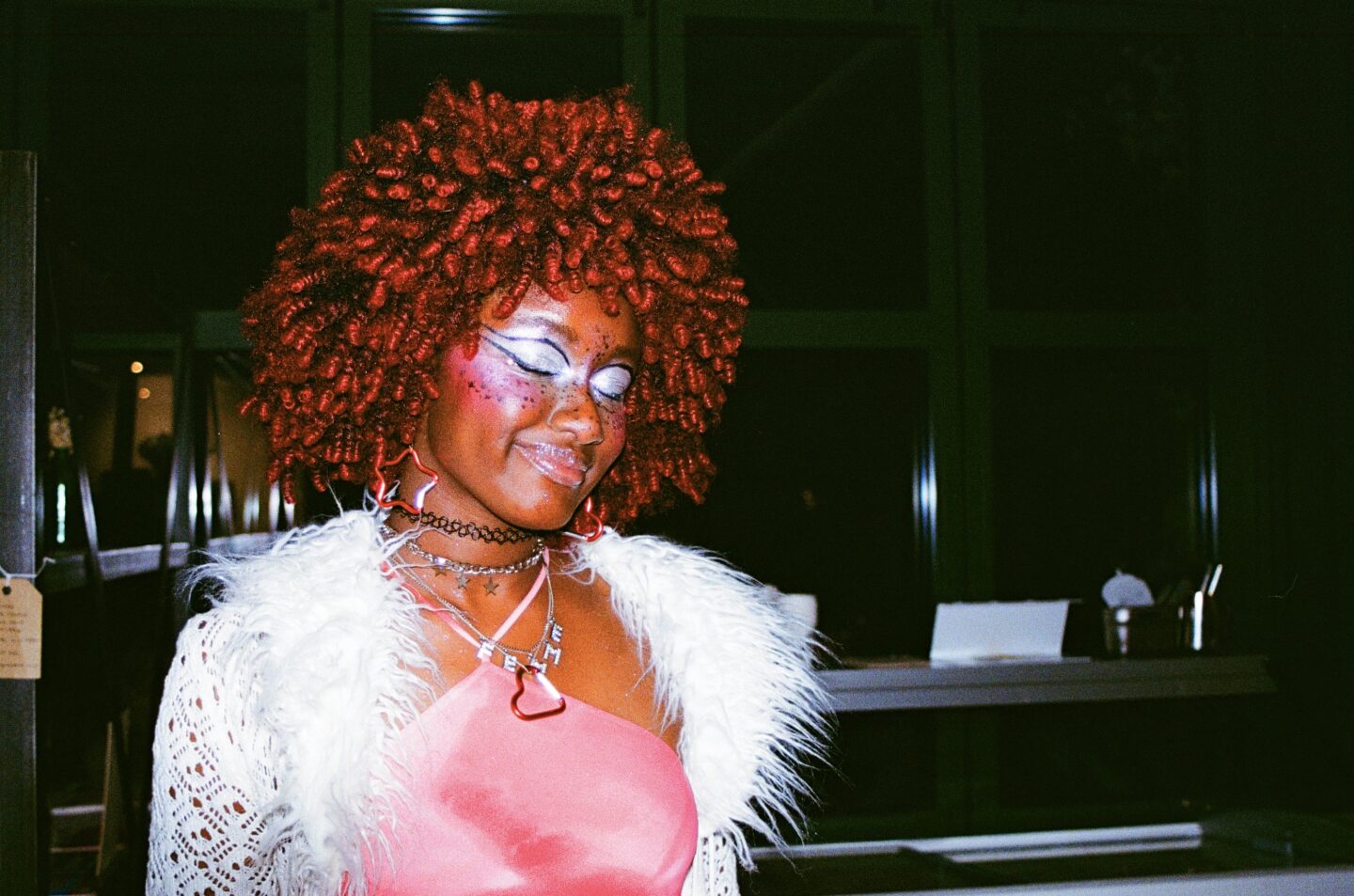 A person with makeup on and eyes closed at a bar