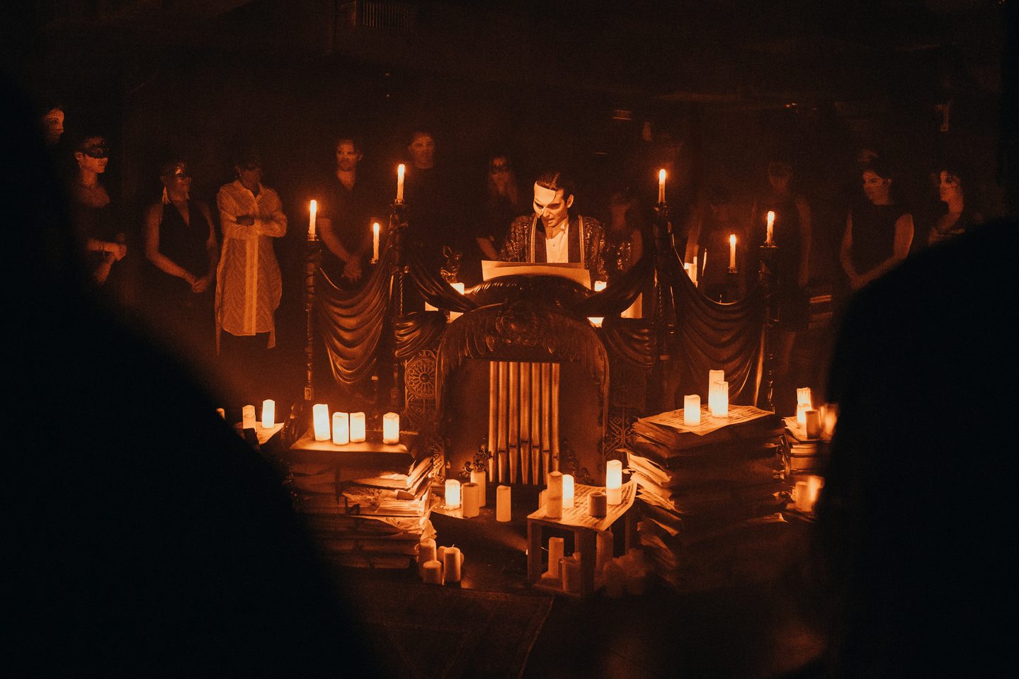 Production photo featuring the phantom of the opera at an altar surrounded by candles